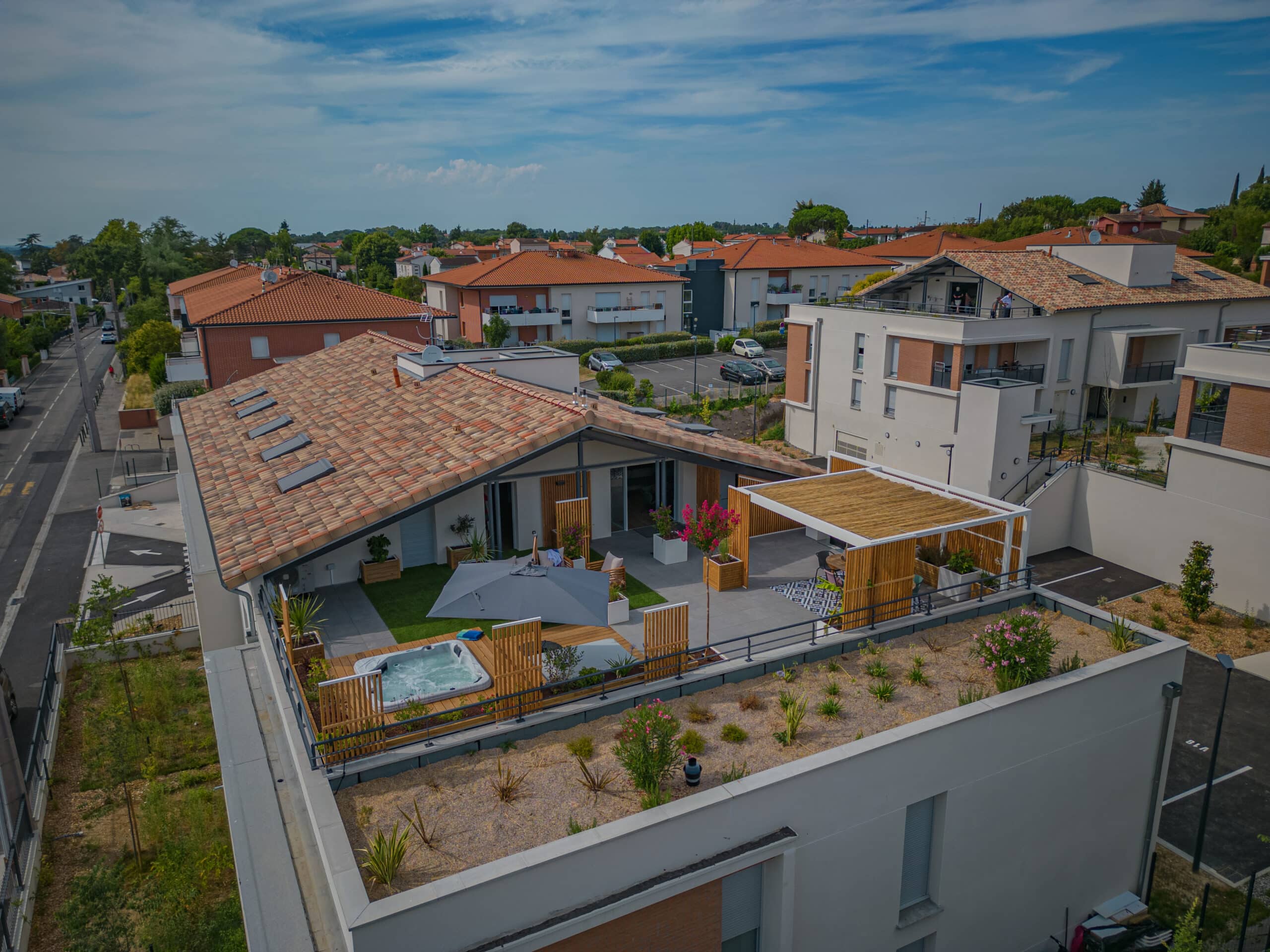 Terrasse de toit haut de gamme avec spa, pergola et jardin végétalisé dans un quartier résidentiel moderne.