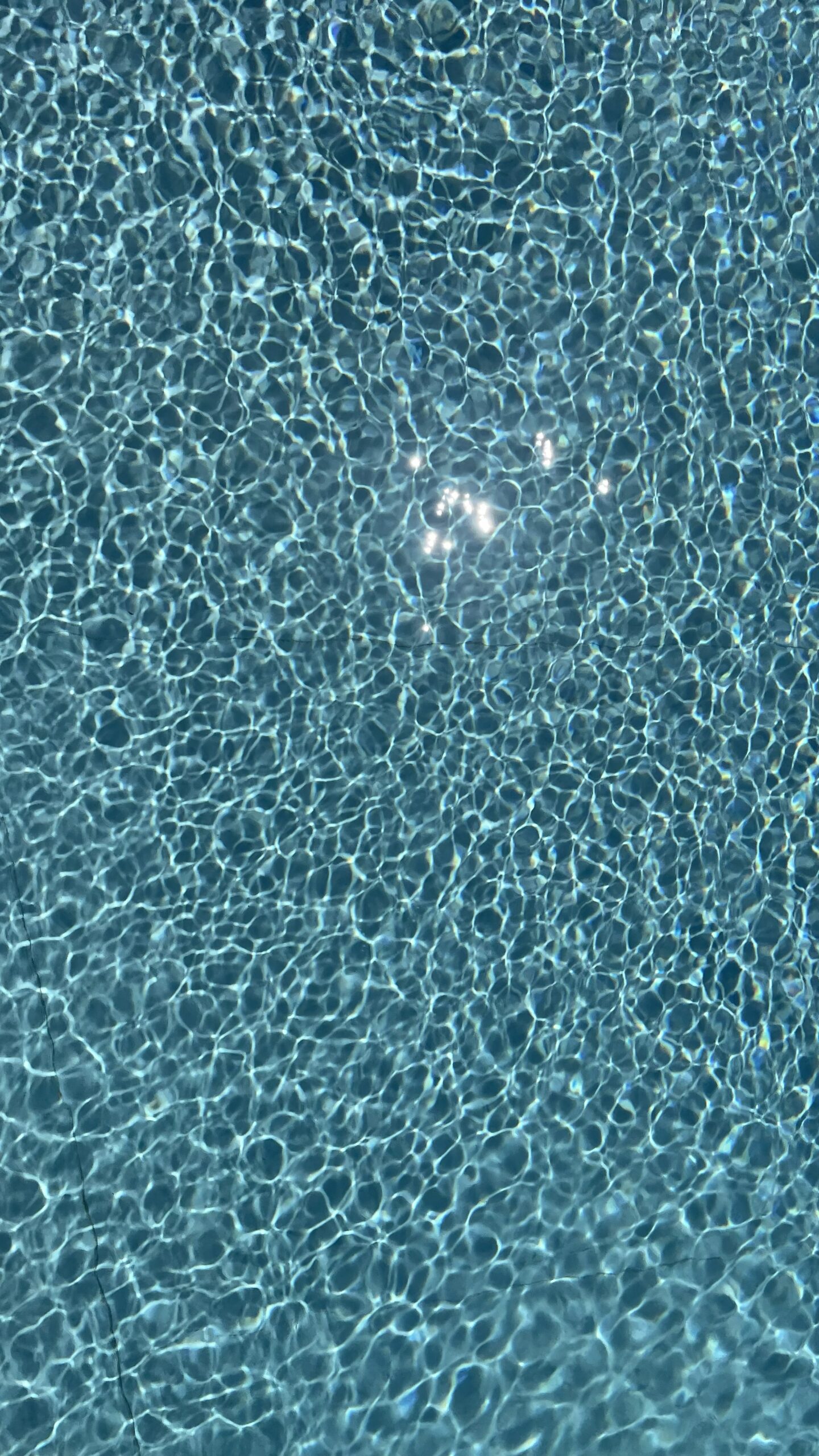 Eau bleue de piscine avec ondulations et reflets de soleil étincelants.
